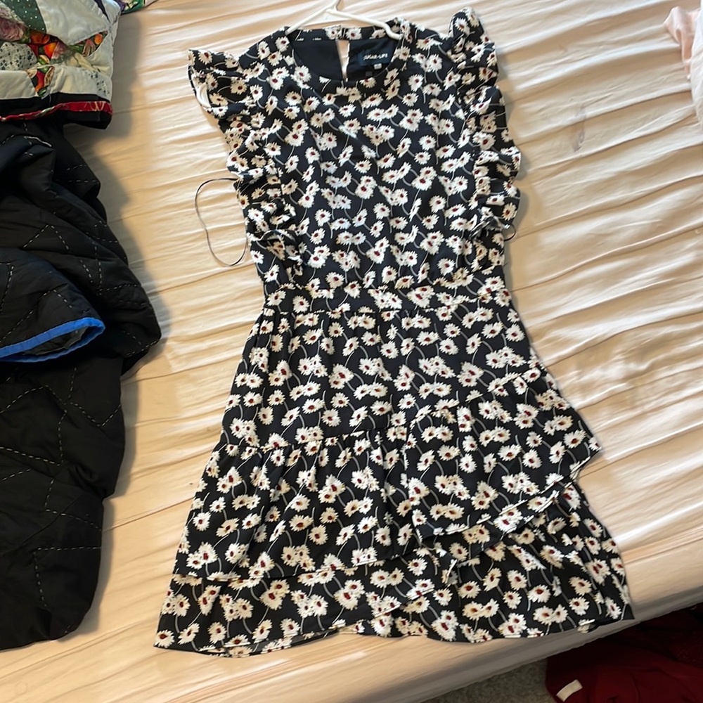 This is a dress with a white daisy pattern on a black background. Knee length.